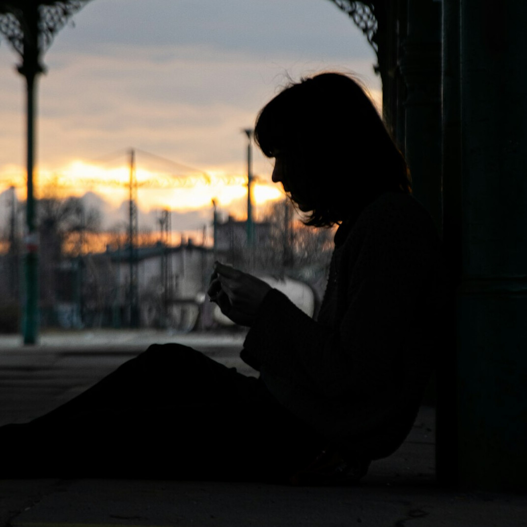 Silhouette of a writer seated by a window writing in a notebook at dusk