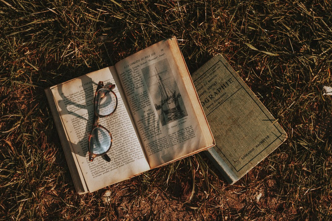 Open antique book with a magnifying glass resting on the pages