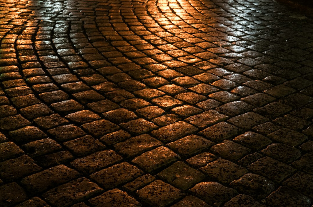 Rainy cobblestone street in Montevideo at night with reflections of streetlights